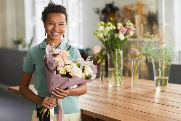 Mujer joven sosteniendo flores en la tienda — Foto de Stock