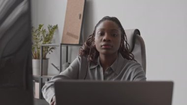 Ofiste çalışan bilgisayar ve dizüstü bilgisayarda program kodları yazan ciddi Afro-Amerikan yazılım geliştiricisinin orta boy yakın çekim görüntüleri.