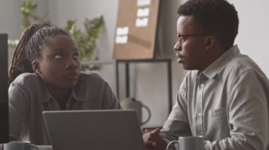 İki genç Afro-Amerikalı erkek ve kadın bilişim programcısının ofiste konuşurken orta ölçekli yakın çekimi.
