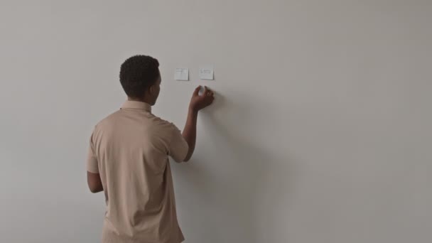 非洲裔美国男性上班族在现代办公室工作场所进行脑力激荡时在墙上贴贴纸的后视镜中照 — 图库视频影像