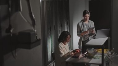 Afrika kökenli Amerikalı ve Kafkasyalı kadınların bilgisayar kullanmaları sunucu odasında oturup konuşmaları.