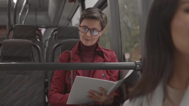 公共交通機関内の窓辺に座っている短髪の白人女性の中程度の閉鎖 昼間のビジネス論文を読む — ストック動画