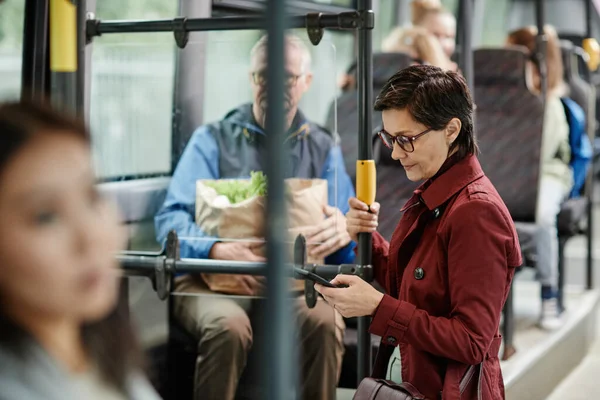 Dorosła kobieta za pomocą smartfona w autobusie — Zdjęcie stockowe