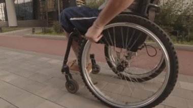 Fiziksel engelli birinin kaldırımda tekerlekli sandalyeyle dolaşırken görüntüsü.