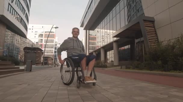 Aufspüren Eines Fröhlichen Jungen Kaukasiers Rollstuhl Der Auf Dem Bürgersteig — Stockvideo