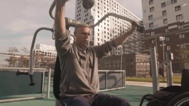 Fiziksel engelli bir beyaz adamın izini sürmek güneşli bir günde spor sahasında ekipman kullanmak.