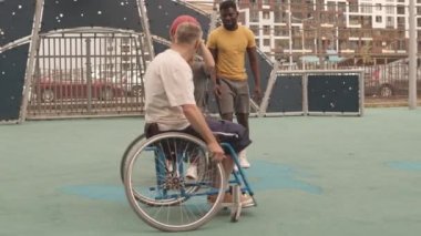 Mahallede basketbol oynayan neşeli beyaz kadın ve erkek arkadaşlarıyla el ele tutuştular. Genç Afrikalı Amerikalı bir adam onları denetliyordu.