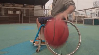Düşük açılı tekerlekli sandalyedeki sporcu kavisli basketbol sahasına damlıyor.