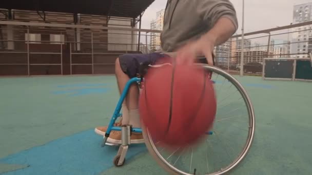 近隣のバスケットボールコートに車椅子ドリブルでクロップドアスリートの低角度円弧 — ストック動画