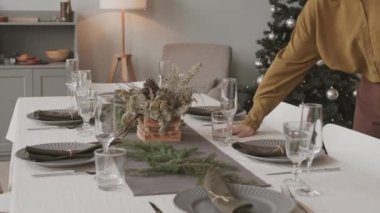 Orta uzunlukta beyaz kadın dekoratör Noel için şenlikli yemek masasına son rötuşları ekledikten sonra oturup portföy için resim çekiyor.
