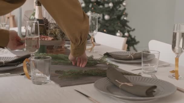 認識できないウェイターの低い角度を追跡昼にクリスマスのために装飾されたお祝いのテーブルに食べ物や軽食で料理を置く — ストック動画