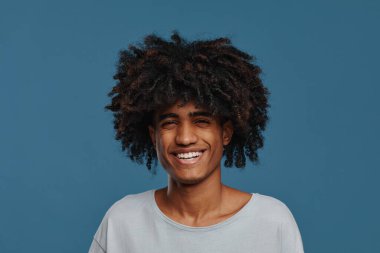 Gülümseyen kıvırcık saçlı genç adam.