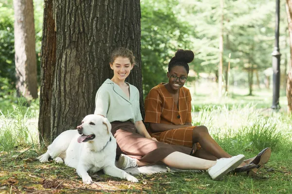 Dos mujeres jóvenes con perro en el parque —  Fotos de Stock