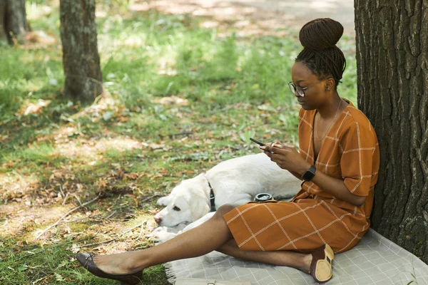 Svart ung kvinna i parken med hund — Stockfoto