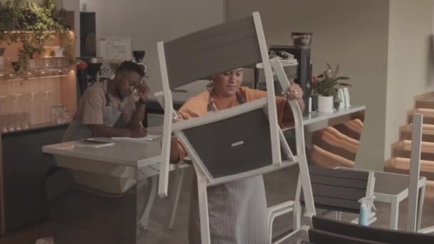 Média Longa Jovem Biracial Mulher Vestindo Avental Organizando Mesas Cadeiras — Vídeo de Stock