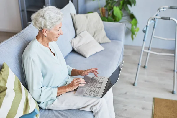 Mujer mayor moderna usando el ordenador portátil en el hogar — Foto de Stock