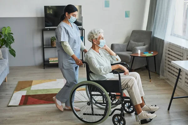 Opiekun osób starszych na wózku inwalidzkim — Zdjęcie stockowe