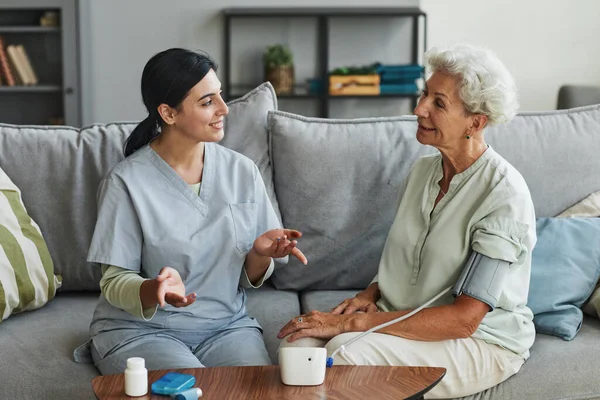 Młoda pielęgniarka rozmawia ze starszą kobietą w domu starców — Zdjęcie stockowe