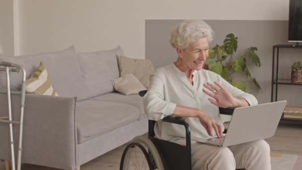 거실에서 휠체어에 앉아서 노트북으로 비디오 대화를 나누고 코카서스 할머니가 가운데 — 비디오