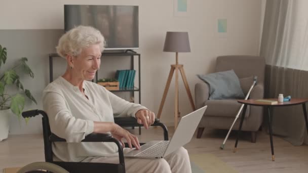 Evinden Kucağında Dizüstü Bilgisayarıyla Sohbet Eden Tekerlekli Sandalyedeki Neşeli Modern — Stok video