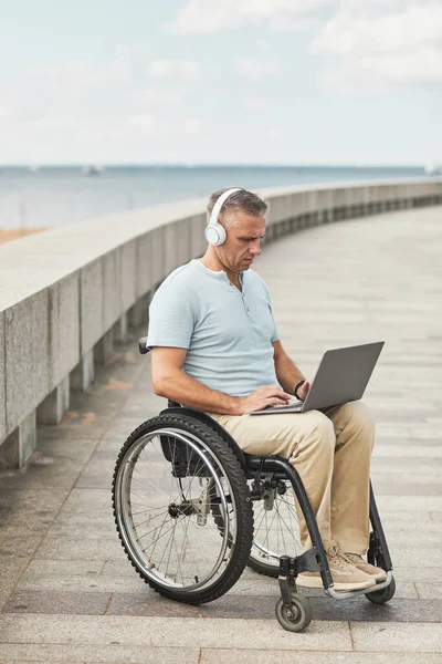 Hombre en silla de ruedas con ordenador portátil al aire libre —  Fotos de Stock