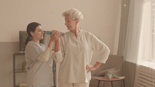 介護の中出しショット女性ソーシャルワーカーヘルプアクティブ老婦人を行うには 一緒に居心地の良いアパートで立っている物理的な腕の練習 — ストック動画