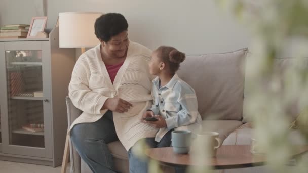 미디엄 아프리카 미국인 과귀여운 손녀는 집에서 소파에 말하고 스마트폰을 했습니다 — 비디오