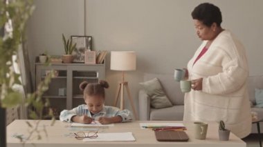 İki at kuyruğu takmış, gündüzleri masa başında oturup keçeli kalem ve kalemle kağıt üzerine resim çizen Afrikalı Amerikalı büyükannelerin gelip kupa getirmesini seven küçük bir kız.