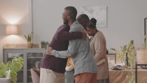 有两个年轻的黑人男子在饭厅里拥抱和握手 家人站在后台 — 图库视频影像