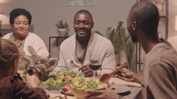 非洲裔美国人家庭中快乐的男女成员在客厅里围坐在桌旁 分享食物 庆祝圣诞节 — 图库视频影像