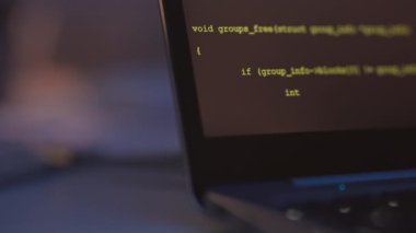Karanlık ofisteki siyah dizüstü bilgisayarda çalışan program kodlarının kapatılması