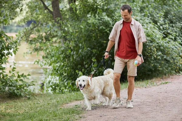 Hombre feliz paseando perro en parque — Foto de Stock