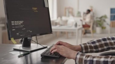 Ofisteki bilgisayar bilgisayarında, bilişim uzmanının tanımlanamayan erkek elinin, program kodlarını yazarken çekilmiş fotoğrafı.