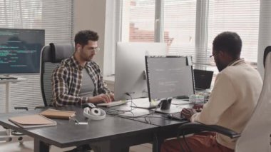Çağdaş ofis program kodlarında bilgisayar üzerinde çalışan iki bilişim uzmanının bıçak görüntüsü.