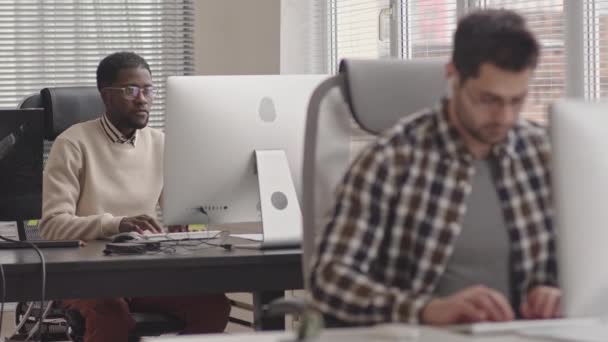 現代のオフィスでコンピュータに取り組んでいる2人の集中多民族のプログラマーのスタブショット — ストック動画
