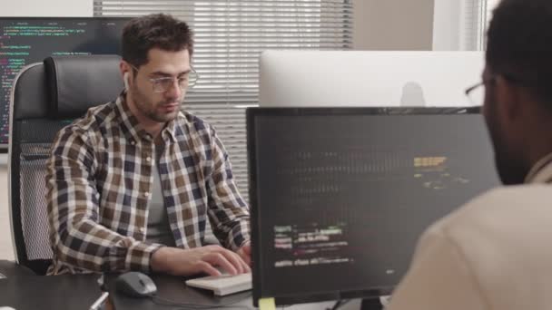 オフィスで新しいソフトウェアを開発するPcコンピュータ上のプログラムコードを書く2つの多民族It専門家のスタブショット — ストック動画