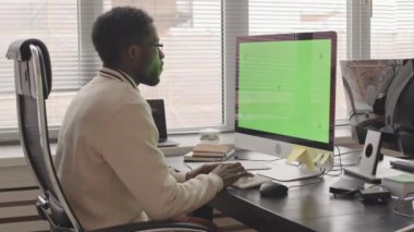 Genç Afro-Amerikan bilişim uzmanının ofisindeki bilgisayarda yazılım geliştirme yazılımının yavaş çekimleri.