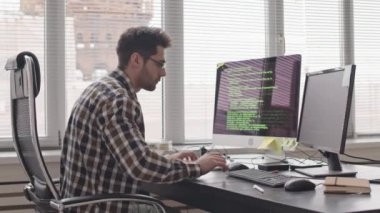 Sakallı, günlük kıyafet ve gözlüklü melez programcının ofis programında yeni yazılım geliştirme programının orta görüntüsü.