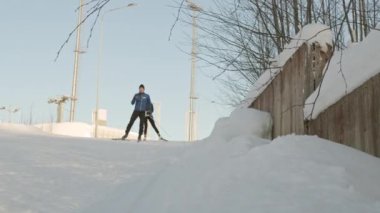 Genç erkek ve beyaz tenli sporcuların spor kıyafetleri giyip yokuş aşağı kayarak durup konuştukları düşük açı.