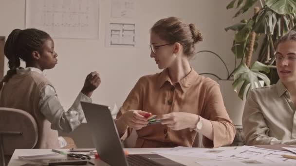 カラーパレットと会話を持つ設計図を見て 現代のオフィスで働くデザイナーの多民族チームのウエストアップショットを追跡 — ストック動画