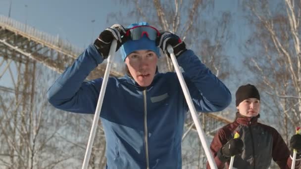 白人男女滑雪者穿着运动服 站在阳光明媚的冬日室外 男人戴上护目镜 — 图库视频影像