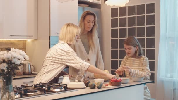 ブロンド白人女性見ます二人の十代の娘作るシリアルとトーストのために朝食 キッチンで話して — ストック動画