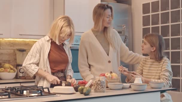 ブロンド白人女性と二人の十代の娘作る朝食 笑顔と話上のキッチン — ストック動画