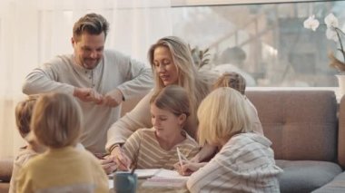 Kafkasyalı kadın ve erkek kanepede oturup kahve masasında beş küçük ve genç çocukla gün içinde gülümseyip konuşuyorlar.