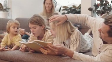 Geniş beyaz anne, baba, genç kız, küçük çocuk kanepede uzanmış, konuşuyor, dinleniyor, kitap okuyor.