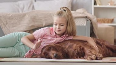 8 yaşındaki bir kızın İrlanda sosisli köpeğini okşayıp okşayarak rahat bir yatak odasında yerde yattığı ağır bir bıçak darbesi.