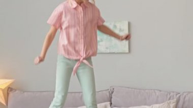 Mutlu liseli kızın, tatlı İrlanda sosisli sandviçiyle yatakta zıplarken yavaş çekimde çekilmiş.