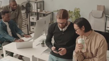 Ofiste çalışan ve iş yerinde sohbet eden dört farklı erkek programcının orta yavaş çekimi.