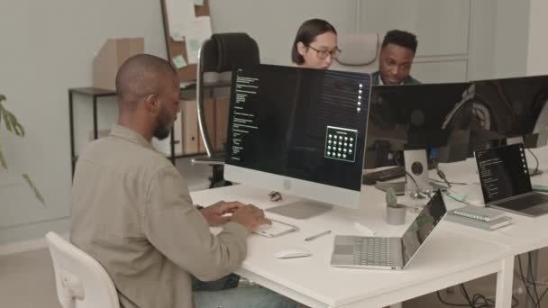 中慢镜头中 年轻的非裔美国程序员在工作场所对着摄像机微笑 而他的不同同事则在幕后进行交谈 — 图库视频影像