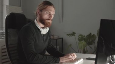 Sakallı ciddi programcının belden aşağı vuruşu. Geceleri bilgisayarda çalışıyor.